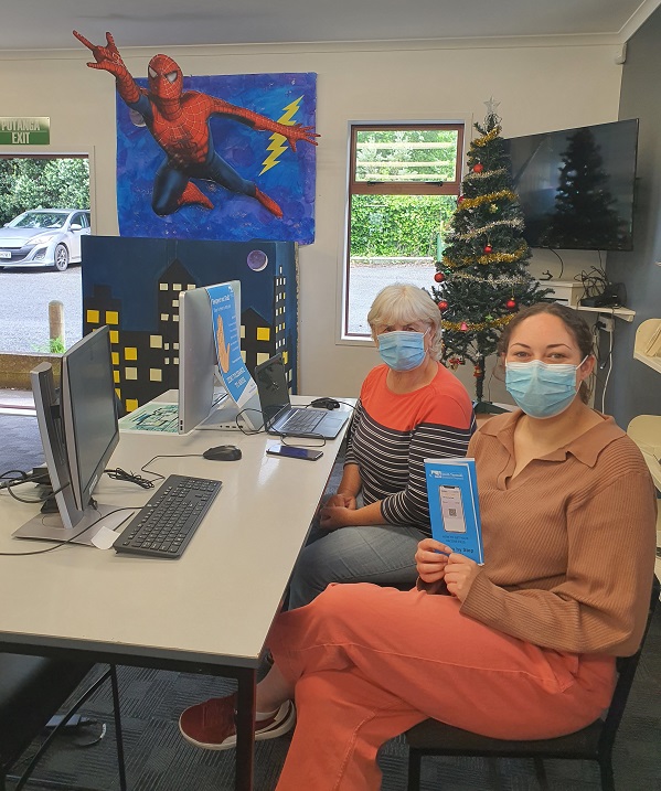 Photo of Waverley LibraryPlus officer, Layne Winiata (front, holding brochure) helping Waverley resident Moira Malpas at the Waverley LibraryPlus centre. 